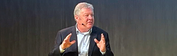 brian higgins as speaker at conference holding hands up