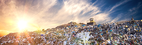 sun rising over large landfill mound