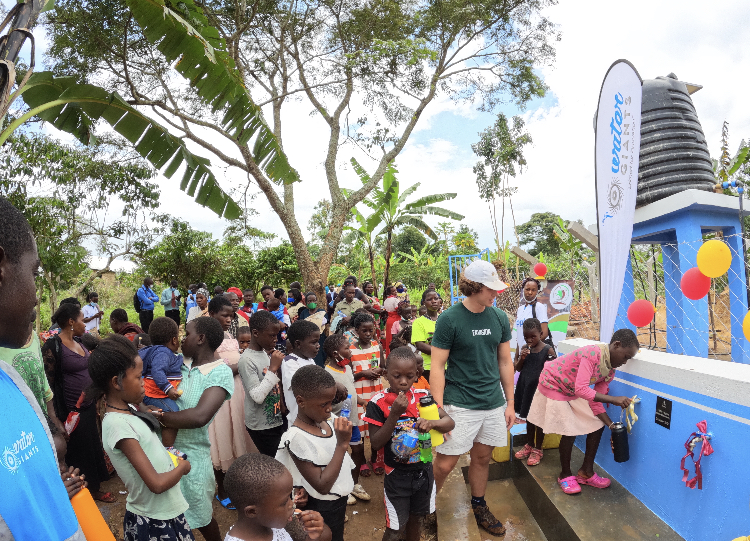Adults providing a large group of people fresh water from a water station