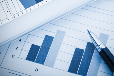 Ballpoint pen resting on paper sheets depicting bar graphs