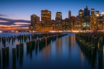 City skyline in late evening with a harbor and wood posts sticking out of the water at low tide in the foreground