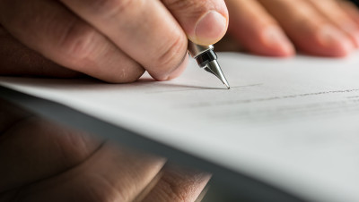 Close-up photo of hands holding a fountain pen and writing on a piece of paper