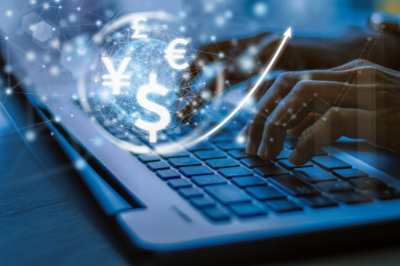 Currency symbols superimposed on an image of hands typing at a laptop keyboard