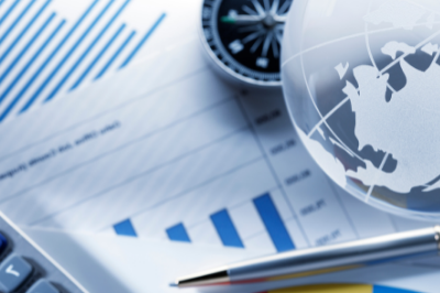 Glass globe on a table with papers depicting charts and graphs