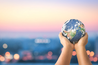 Hands holding a miniature version of the earth and raising it to the sky