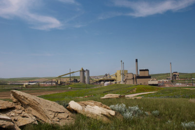 Large rocks and boulders in the foreground and a coal-fired power plant behind them