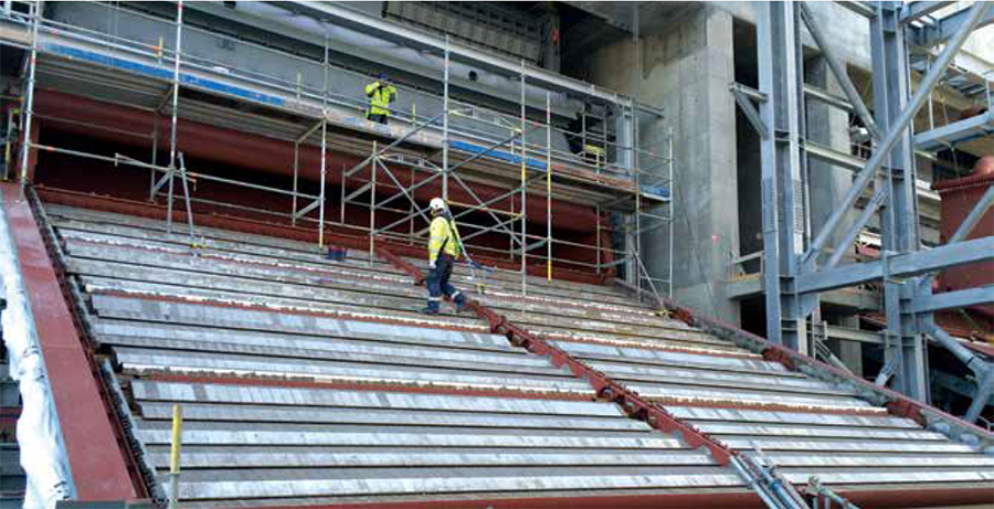 a man walking on an open combustion grate at a power plant under construction
