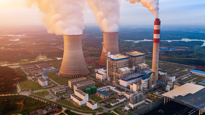 aerial view of a power plant with steam coming out of the cooling towers and stacks