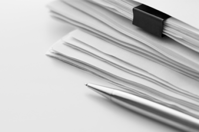 ballpoint pen resting next to a stack of papers